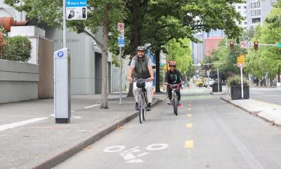A man and a child bike down 2nd Ave on the protected bike lane